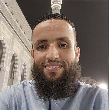 صورة للرجل الذي يعبر عنه باللغة العربية، ويتميز بشعر طبيعي وشعر بنفسجي على وجهه، ويبلغ عن نفسه باللغة العربية.